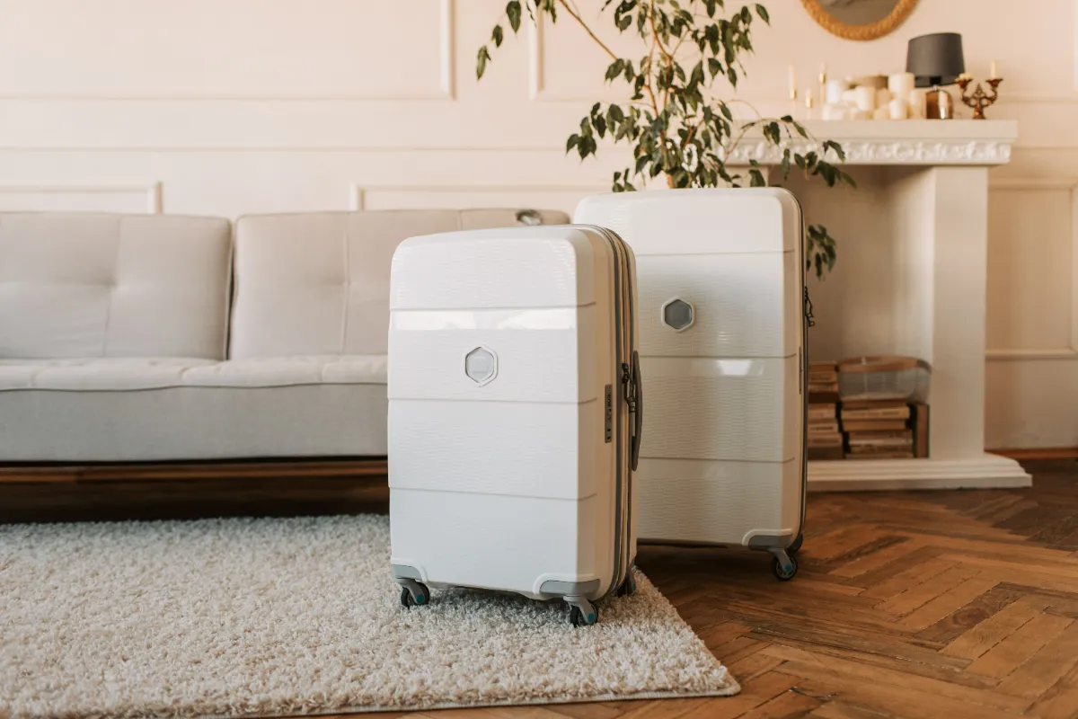 A large suitcase and a smaller case standing packed on a living-room floor beside a sofa